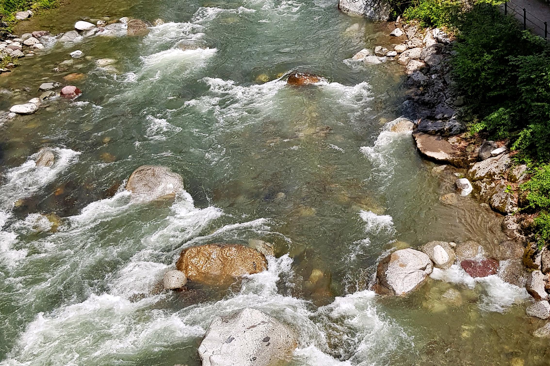 Bachlauf mit großen Steinen um die das Wasser herumströmt